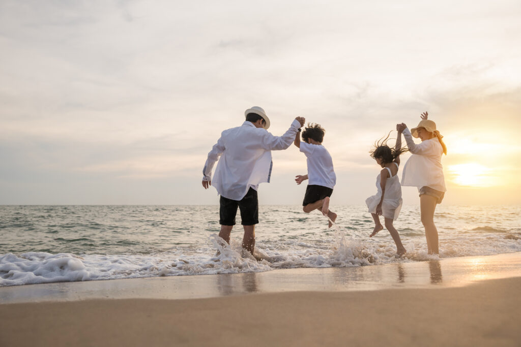 happy family have fun jumping on beach in holiday at sunset