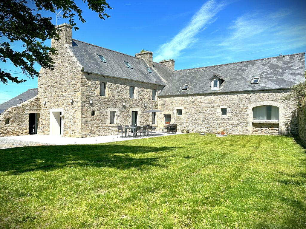 Propriété bretonne en Pierre avec terrasse, chaises et table. Gazon devant maison