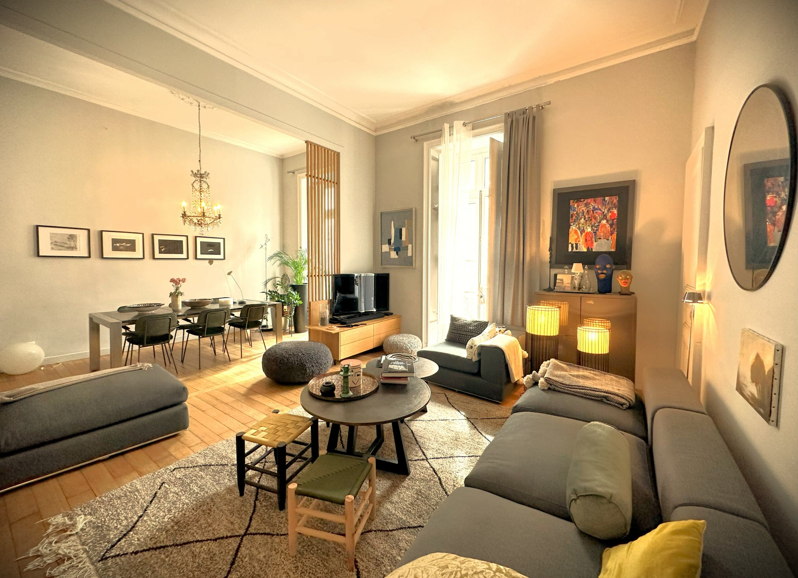Double séjour d'un appartement élégant, style hausmannier, canapé gris, table en fond