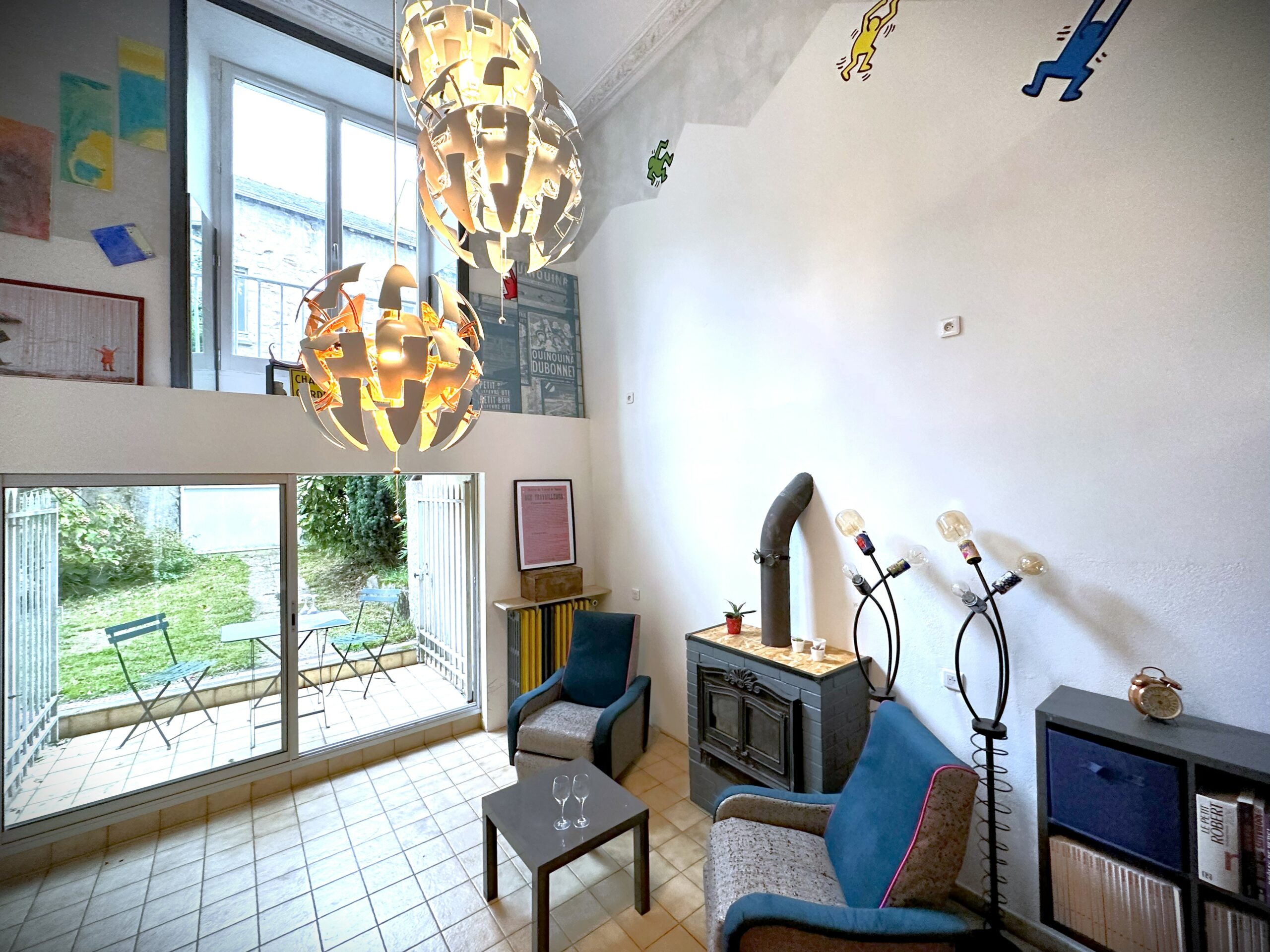 Salon/séjour d'un loft avec insert à bois, le tout donnant sur jardin avec portes fenêtres