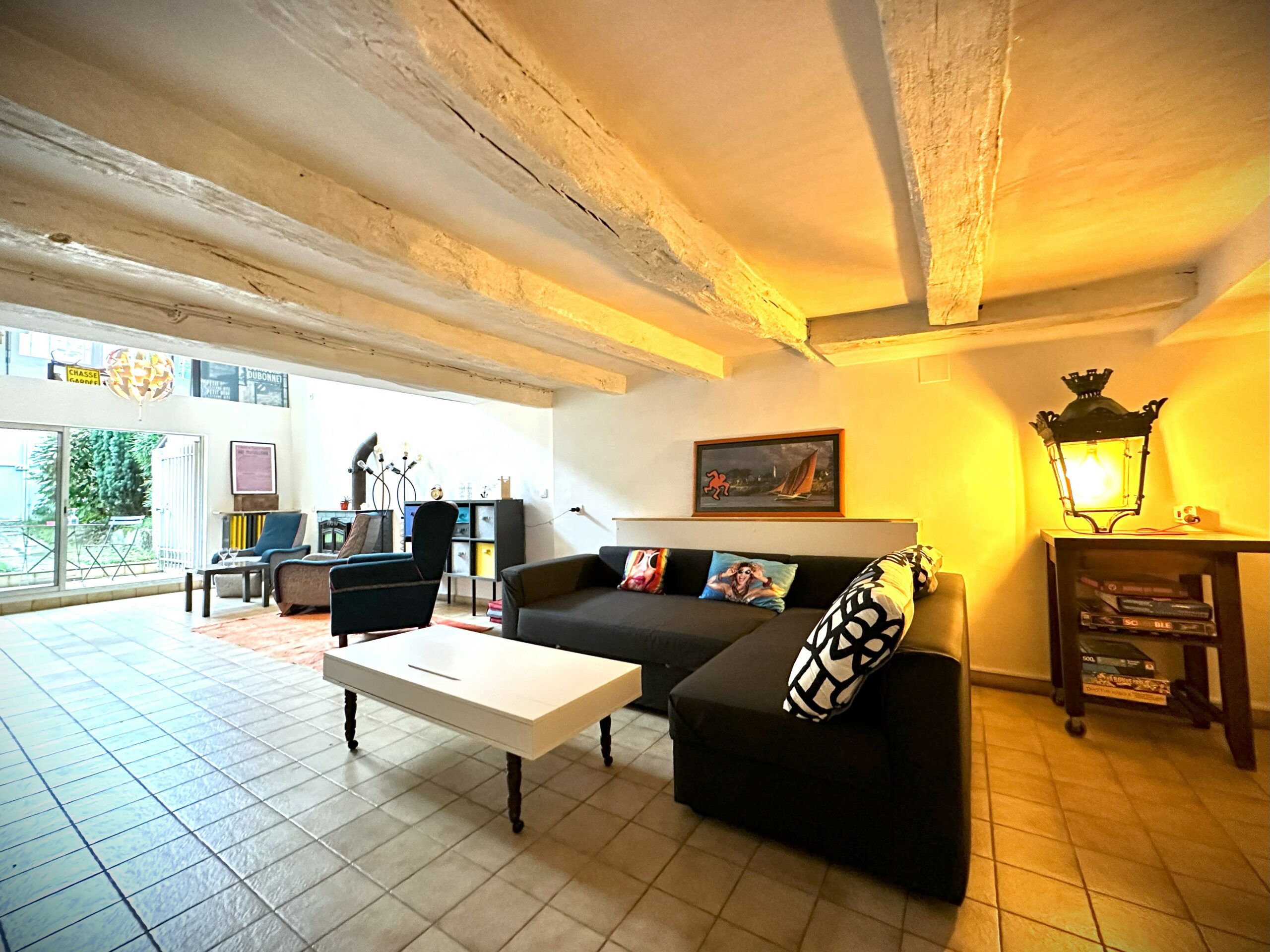 Salon bas de plafond, sol carrelage, canapé, le tout donnant sur jardin