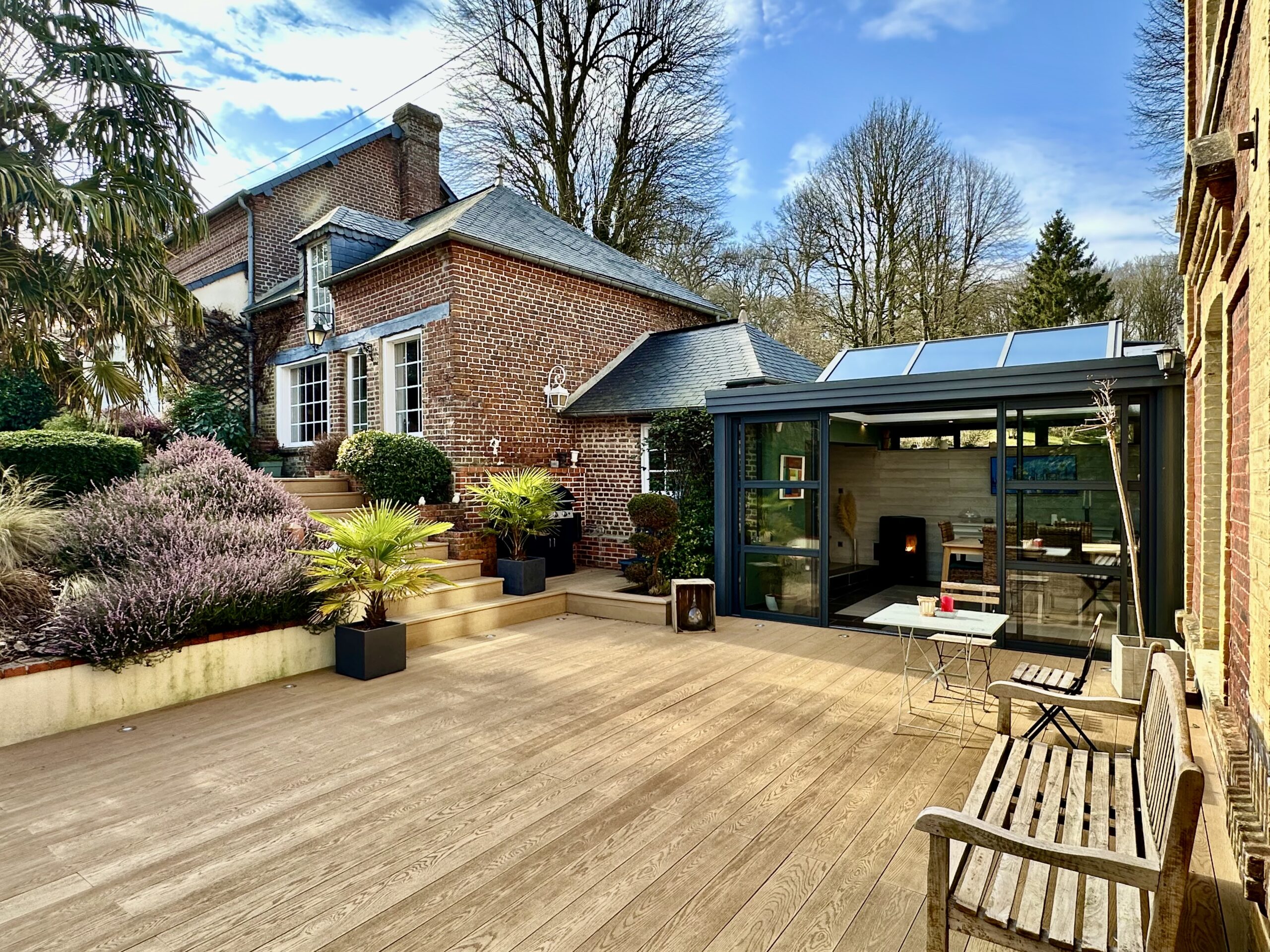 Grande terrasse paysager, véranda et dépendance en brique, maison normande