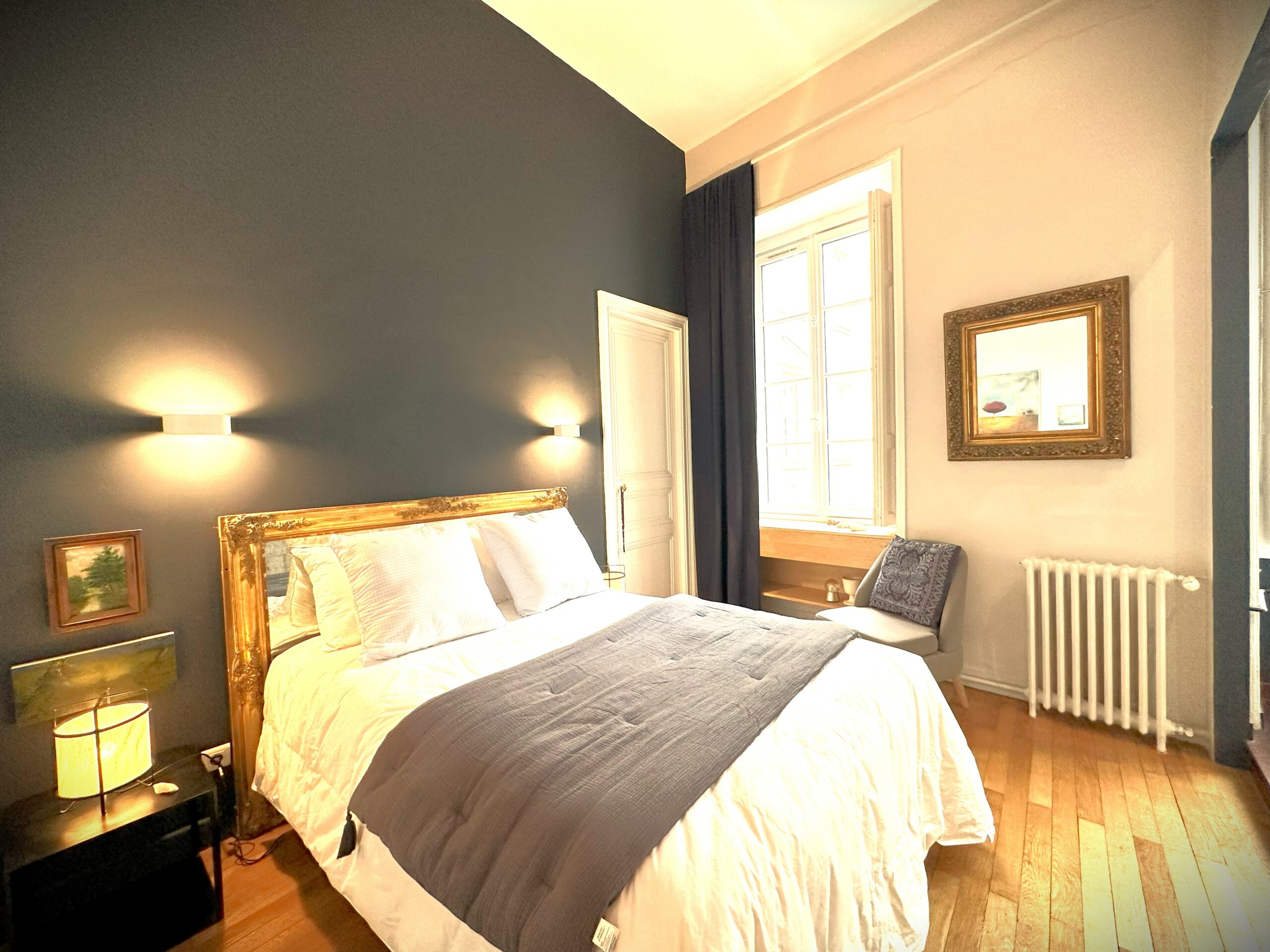 Chambre avec plaid, élégant, mur bleu foncé et blanc, sol parquet, fenêtre lumineuse