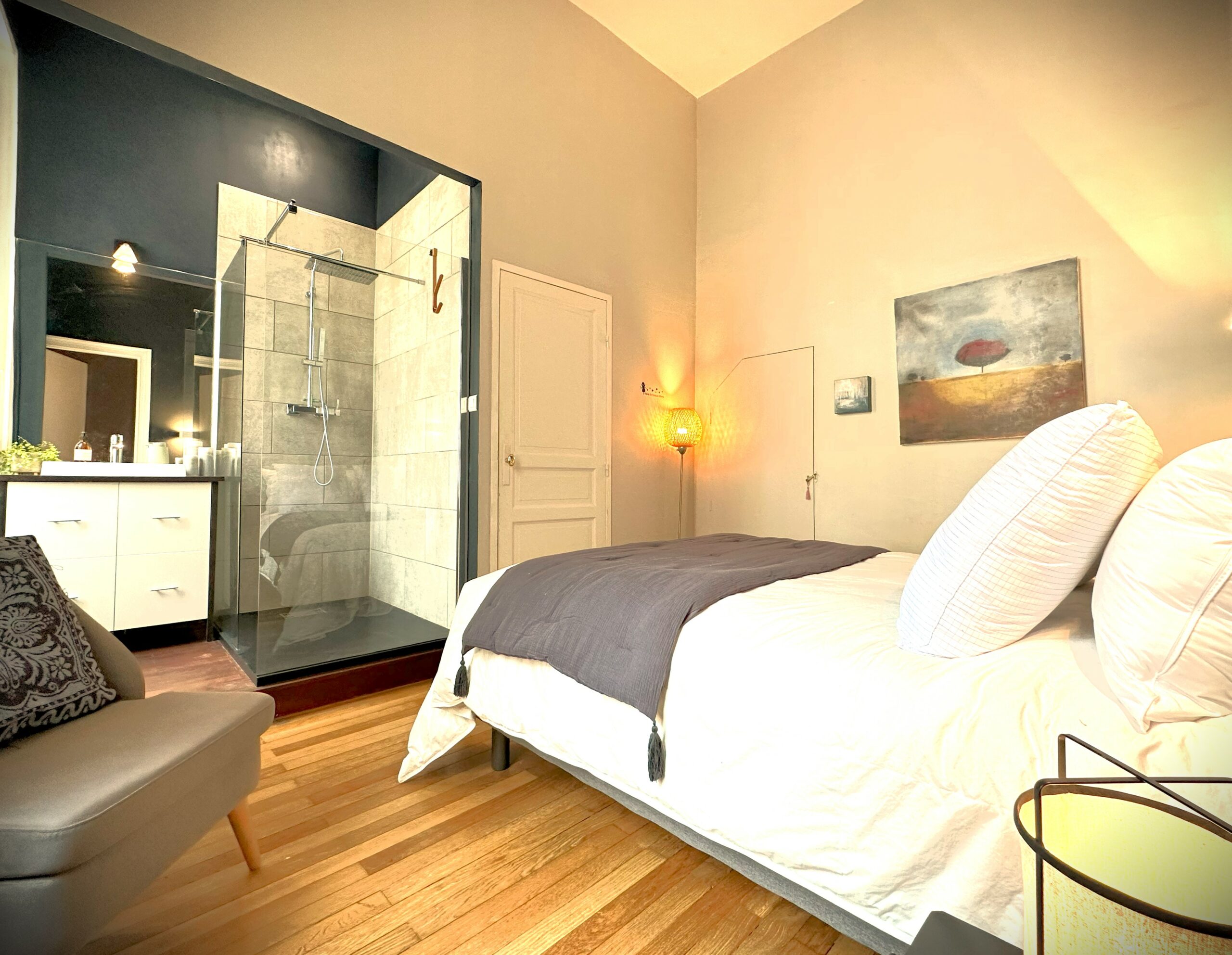 Suite parentale avec grand lit et salle de douche ouverte sur la chambre