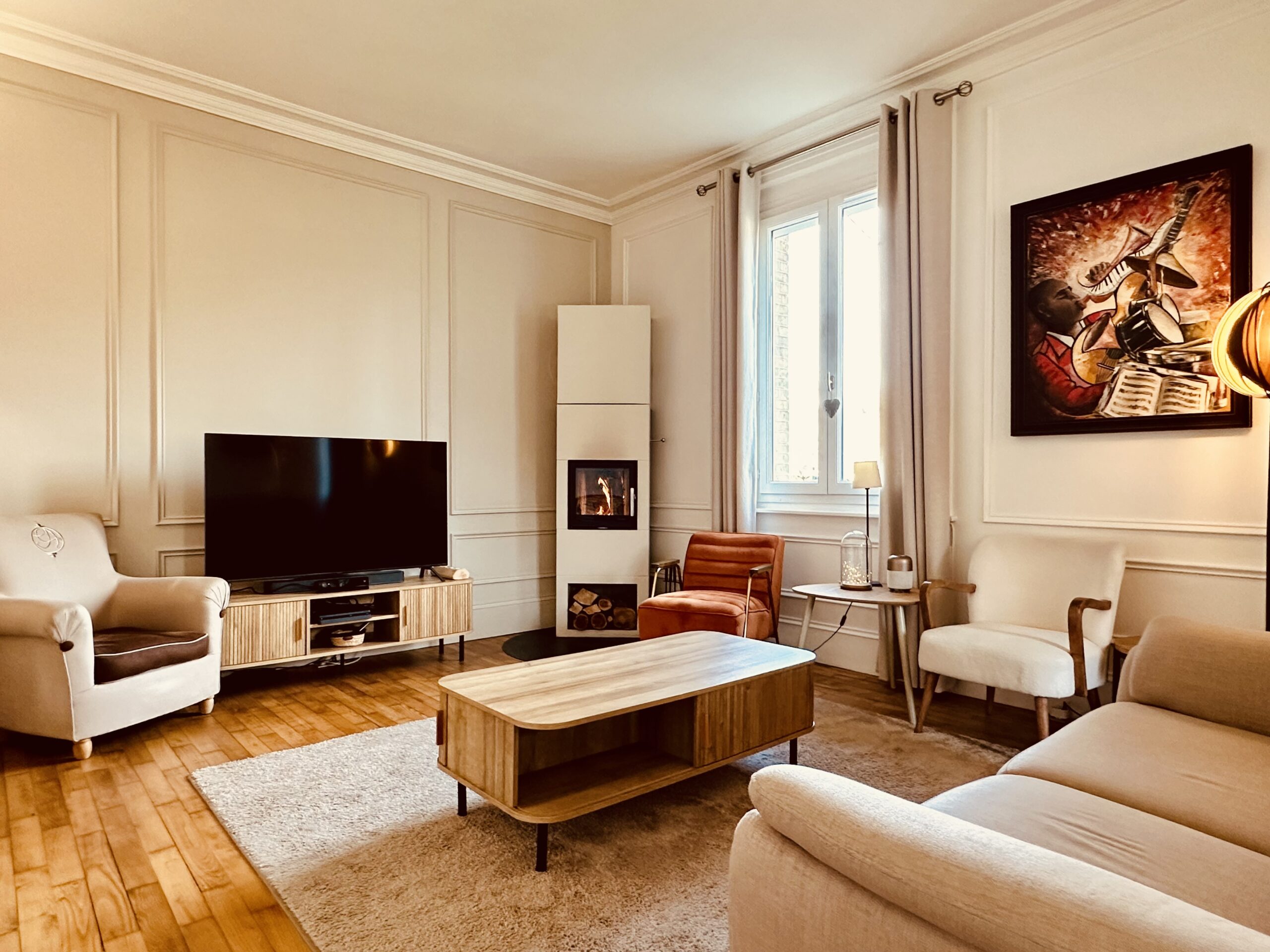 Salon avec canapé, TV et table basse. Insert à bois. Fenêtre donnant sur jardin