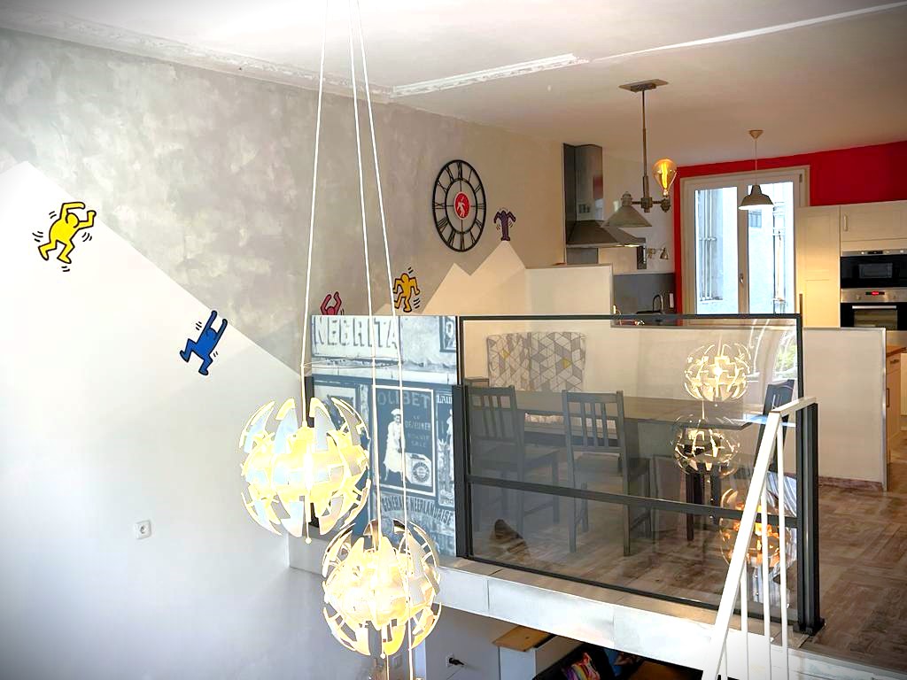 Salon loft avec barrière en verre entre les deux étages, vue sur lustres modernes
