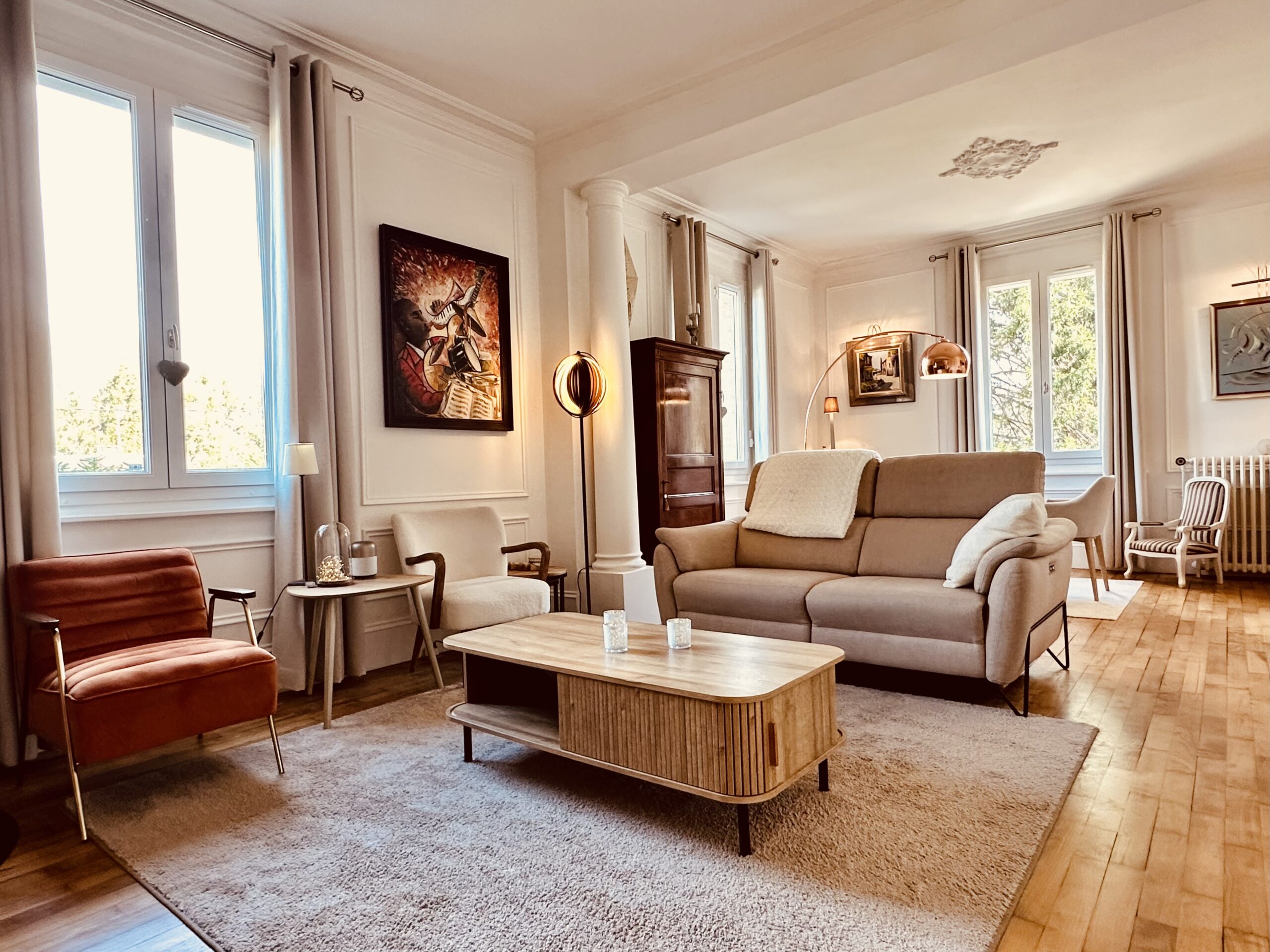 Double séjour maison de maître, avec canapé et table, dans les tons beige, 3 fenêtre sur jardin