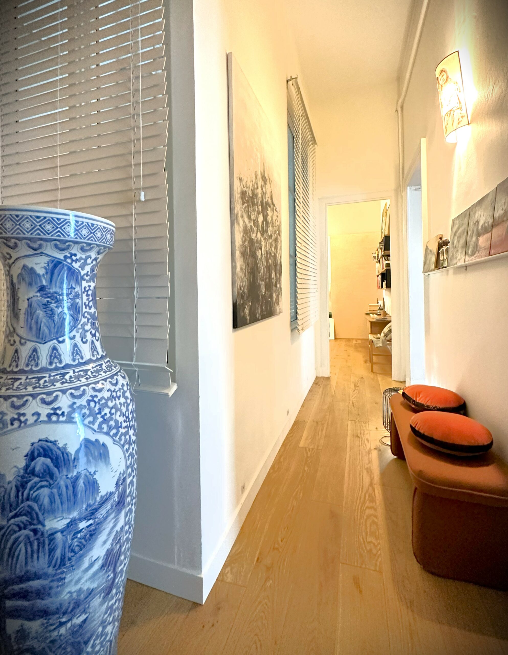 Couloir appartement élégant avec grande vase porcelaine et petit canapé d'appoint