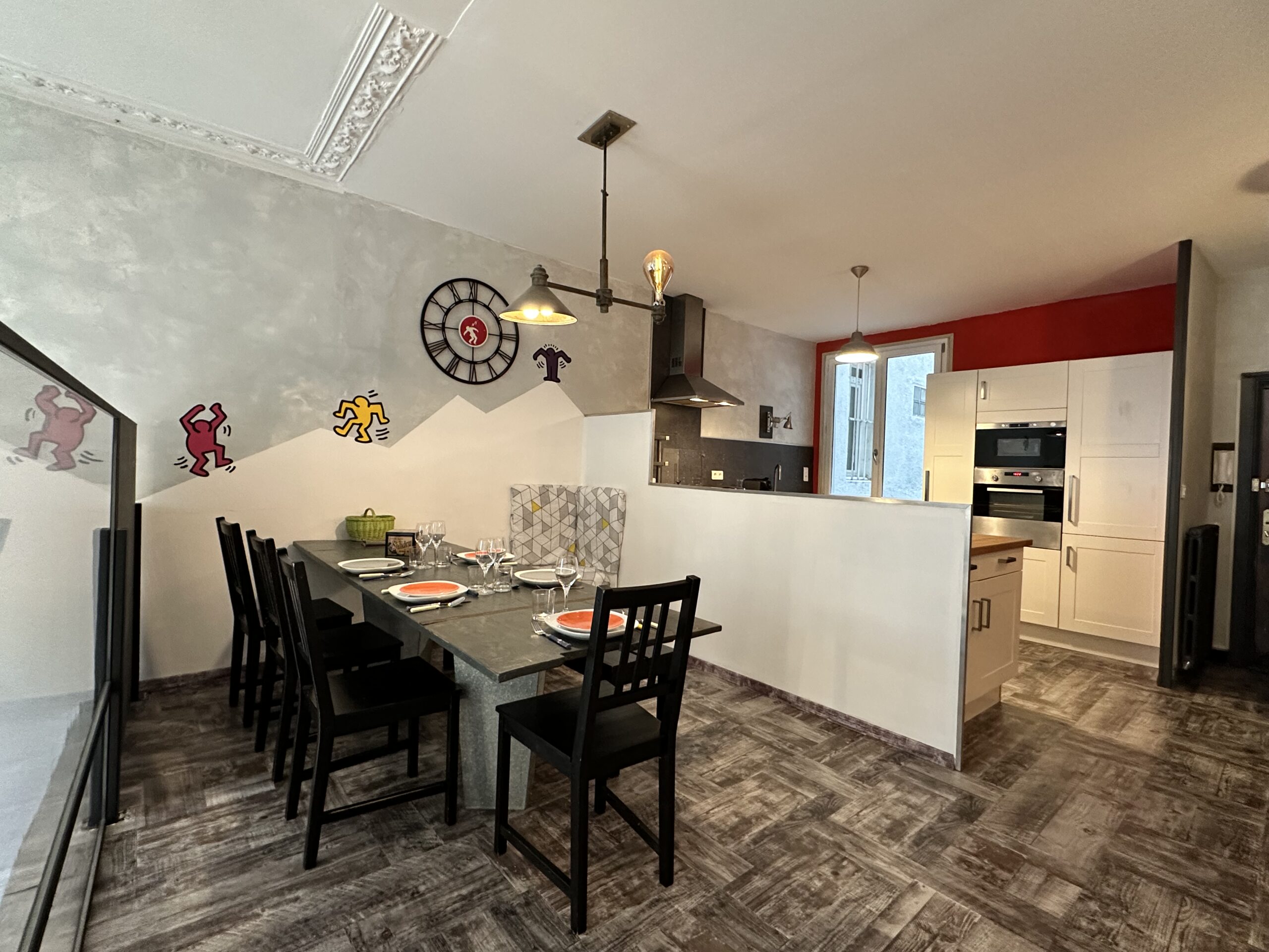 Salon loft avec cuisine ouverte, séparée par petit mur. Table à manger dressée