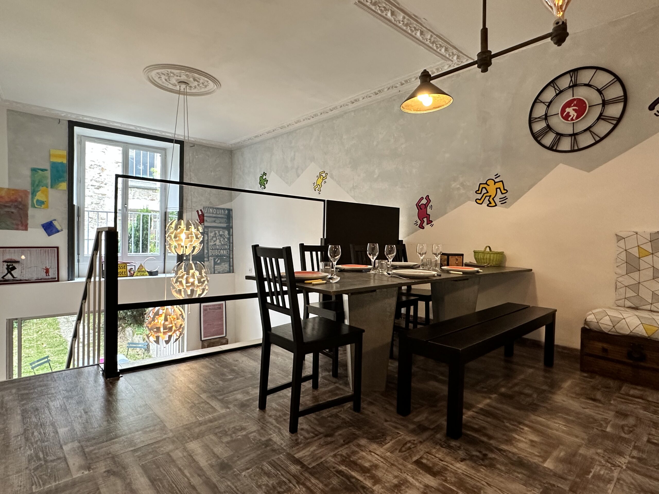Salon d'un loft avec table à manger. Escalier descendant vers fenêtre et jardin