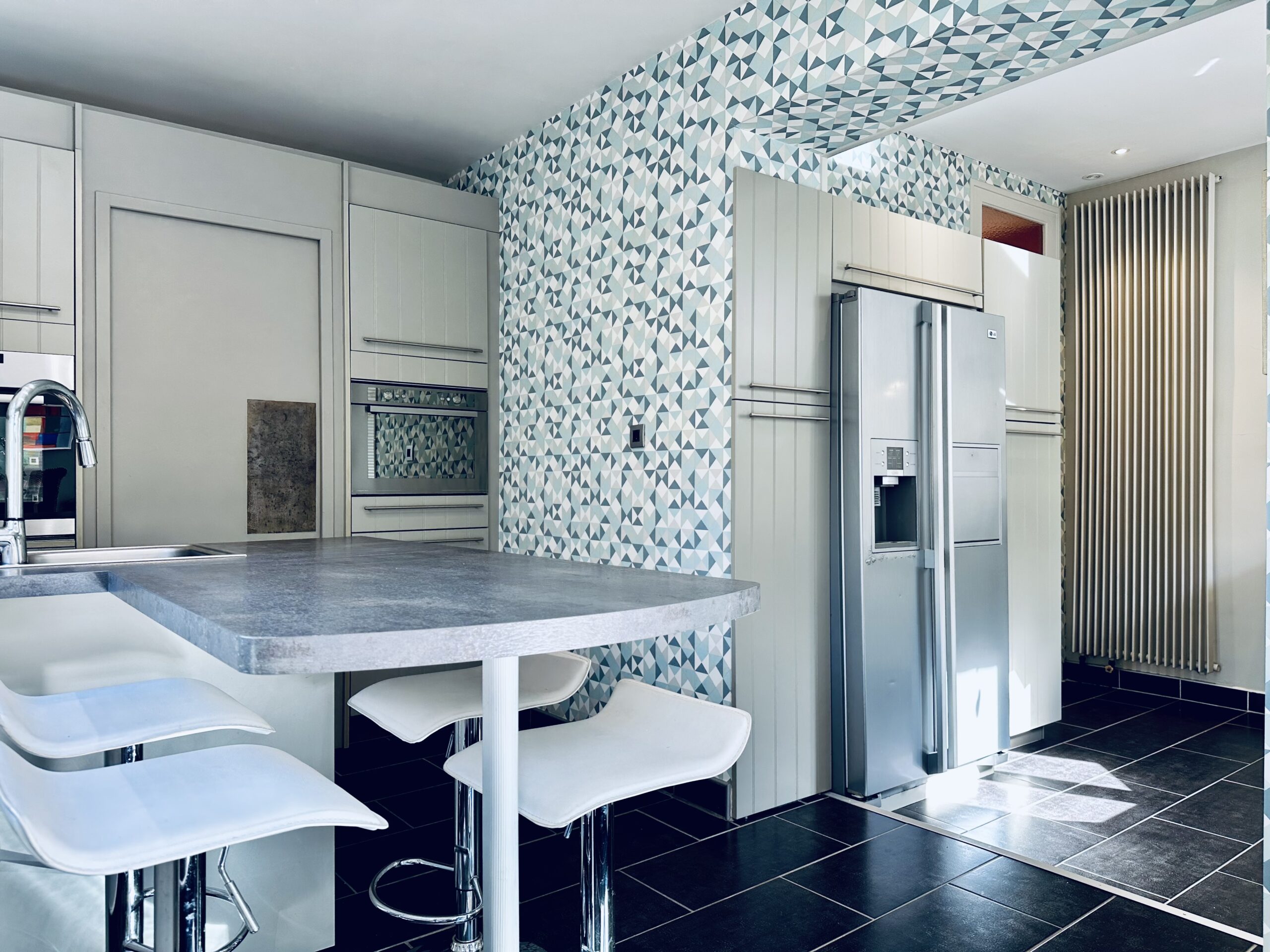 Cuisine dans les tons bleu et blanc, table bar avec évier, frigo américain