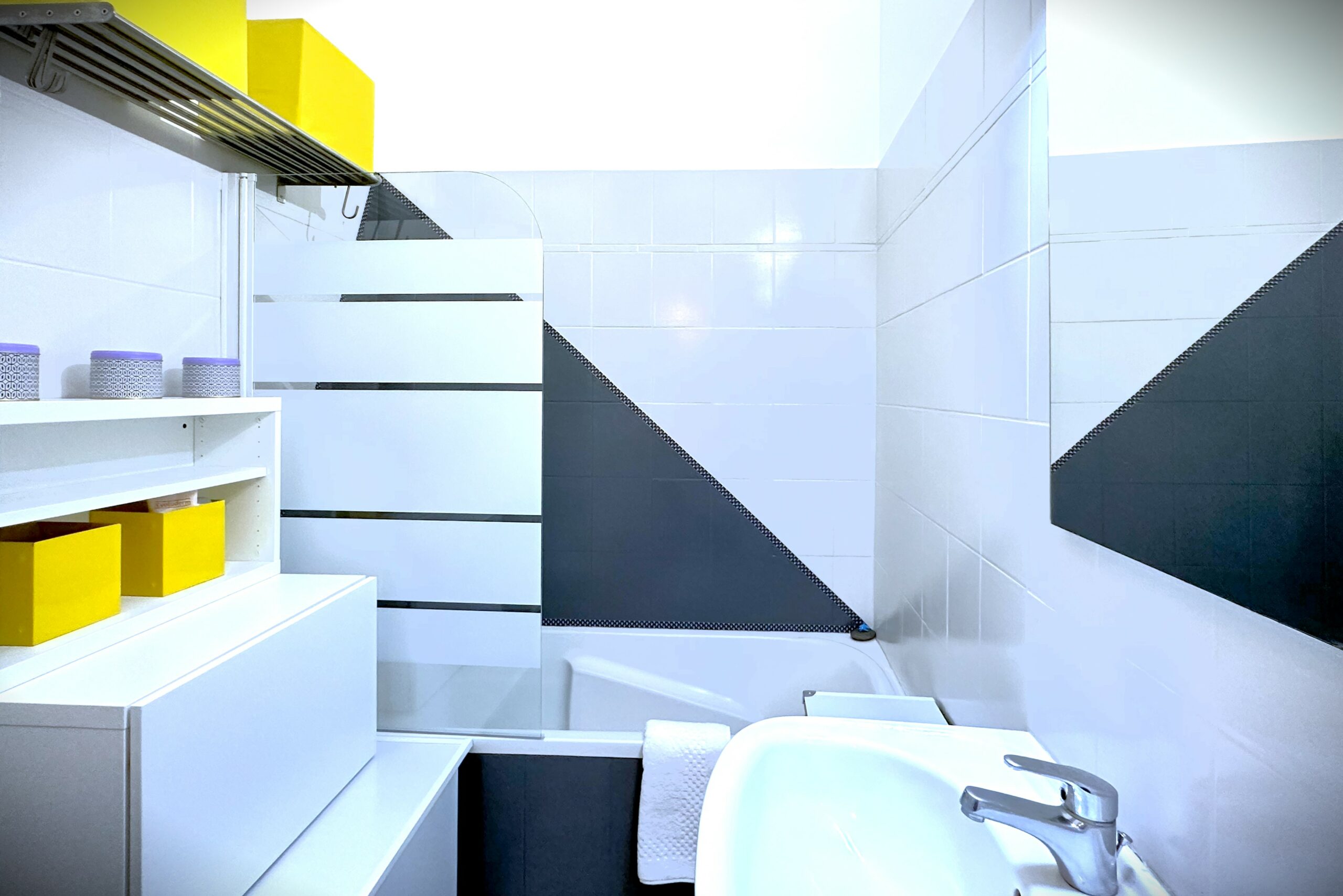 Salle de bain style graphique, jaune gris et noir. Baignoire et évier