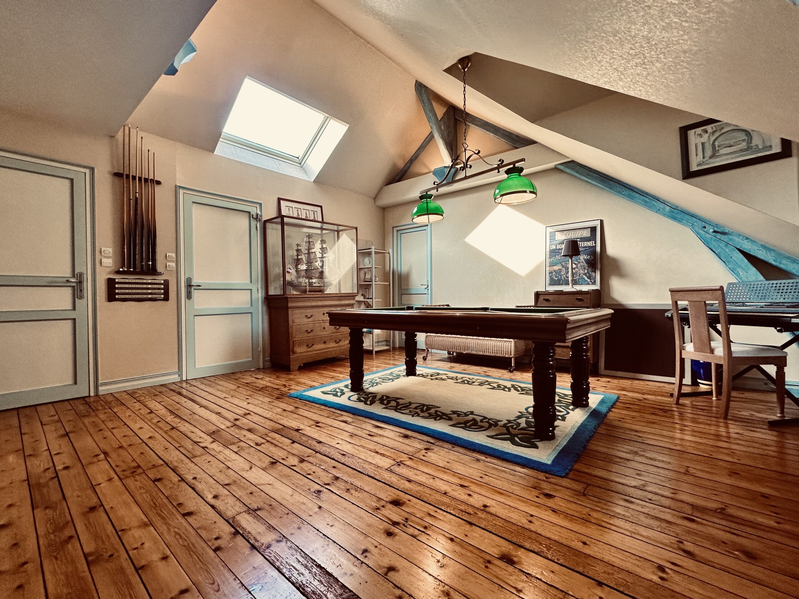 Salle de jeux sur parquet ancien avec billard et poutres apparentes